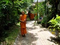 Smiling Buddhist monk poses with a bouquet of flowers in his hands on a quiet street in Bangkok, Thailand
