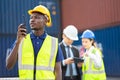 Smiling builder Engineering in hardhat with walkie talkie over group of builders at construction site Royalty Free Stock Photo