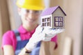 Smiling builder in hard hat holds miniature house