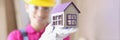 Smiling builder in hard hat holds miniature house