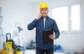 Smiling builder in helmet calling on smartphone