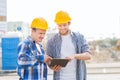 Smiling builders in hardhats with tablet pc