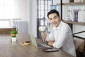 Smiling business Asian man with white shirt sitting feel relax and holding cup of coffee during working with laptop Royalty Free Stock Photo