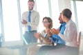 Smiling business colleagues applauding while sitting at table in new office during meeting Royalty Free Stock Photo