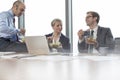 Smiling business colleagues eating lunch while sitting in boardroom during meeting at office Royalty Free Stock Photo