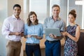 Smiling business colleagues using mobile phone, digital tablet and laptop Royalty Free Stock Photo