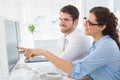 Smiling business coworkers pointing screen of computer