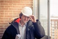 Smiling business engineer with white safety helmet holding blueprint project plan on brick building background, happy Royalty Free Stock Photo