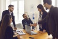 Smiling business partners shaking hands after successful negotiations with colleagues in office Royalty Free Stock Photo