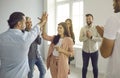 Smiling business people give each other a high five while colleagues are applauding Royalty Free Stock Photo