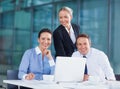 Smiling business people. Three business people smiling with laptop coffee cups on table. Royalty Free Stock Photo