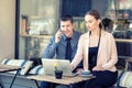 Smiling business people using laptop at cafe terrace while talking on phone Ã¢â¬â remote working Royalty Free Stock Photo