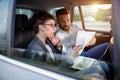 Business people working on paperwork in backseat of car