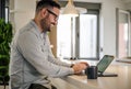 Smiling businessman working on laptop while sitting at desk in office Royalty Free Stock Photo