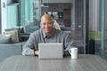 Smiling business senior old elderly Black American man, African person working from home on table with computer notebook laptop in Royalty Free Stock Photo