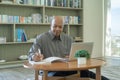 Smiling business senior old elderly Black American man, African person working from home on table with computer notebook laptop in Royalty Free Stock Photo