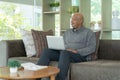 Smiling business senior old elderly Black American man, African person working from home on table with computer notebook laptop in Royalty Free Stock Photo