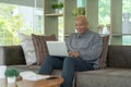 Smiling business senior old elderly Black American man, African person working from home on table with computer notebook laptop in Royalty Free Stock Photo
