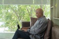 Smiling business senior old elderly Black American man, African person working from home on table with computer notebook laptop in Royalty Free Stock Photo