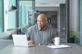 Smiling business senior old elderly Black American man, African person working from home on table with computer notebook laptop in Royalty Free Stock Photo