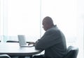 Smiling business senior old elderly Black American man, African person working from home on table with computer notebook laptop in Royalty Free Stock Photo