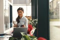 Smiling business woman holding phone and looking at camera while working on laptop in office Royalty Free Stock Photo