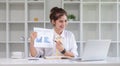 Smiling business woman presenting work. A businesswoman holds a pen and points at a document with work results