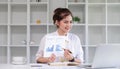 Smiling business woman presenting work. A businesswoman holds a pen and points at a document with work results