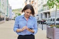 Smiling business woman reading typing looking at smartphone screen walking along city street Royalty Free Stock Photo