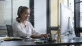 Smiling business woman sitting in bright modern office and working with computer Royalty Free Stock Photo