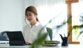 Smiling business woman sitting in bright modern office and working with computer laptop Royalty Free Stock Photo