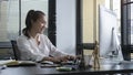 Smiling business woman sitting in bright modern office and working with computer Royalty Free Stock Photo