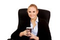 Smiling business woman sitting on a chair and holding cup of coffee Royalty Free Stock Photo