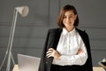 A smiling business woman wearing a white shirt and a black jacket on her shoulders is standing with her arms crossed in front of Royalty Free Stock Photo