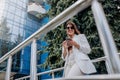 Smiling business woman in white suit and sunglasses using phone during break standing near modern office building Royalty Free Stock Photo