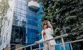 Smiling business woman in white suit and sunglasses using phone during break standing near modern office building Royalty Free Stock Photo