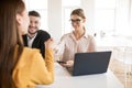 Smiling business woman with mobile phone in hand happily shaking applicant hand. Young employers spending job interview