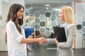 Smiling business women shaking hands in meeting room at creative office. Royalty Free Stock Photo