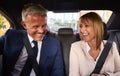 Smiling Businessman And Businesswoman In Back Of Taxi Driving To Office Meeting Together