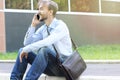 Smiling businessman in casual clothes with leather brief bag sit