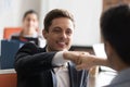 Smiling businessman employee fists bumping with colleague close up