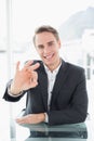 Smiling businessman gesturing okay sign at office desk Royalty Free Stock Photo