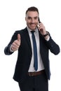 Smiling businessman giving thumbs up and talking on phone Royalty Free Stock Photo