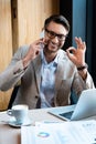 Businessman in glasses talking on smartphone and showing okay sign in cafe Royalty Free Stock Photo