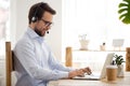 Smiling businessman in headset working on laptop make conference videocall Royalty Free Stock Photo