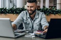 Smiling businessman hipster works simultaneously on two laptops, develops business plan. High labor productivity.