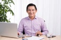 Smiling businessman at his desk with laptop and documents in his Royalty Free Stock Photo