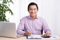 Smiling businessman at his desk with laptop and documents in his Royalty Free Stock Photo