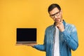 Smiling businessman holding blank laptop screen isolated over yellow background Royalty Free Stock Photo