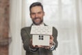 smiling businessman holding symbolic architectural house model focus on foreground Royalty Free Stock Photo